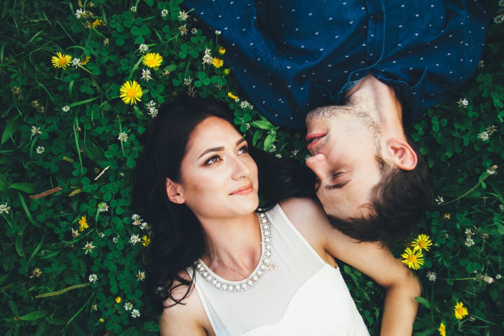 A couple lying on grass facing each other